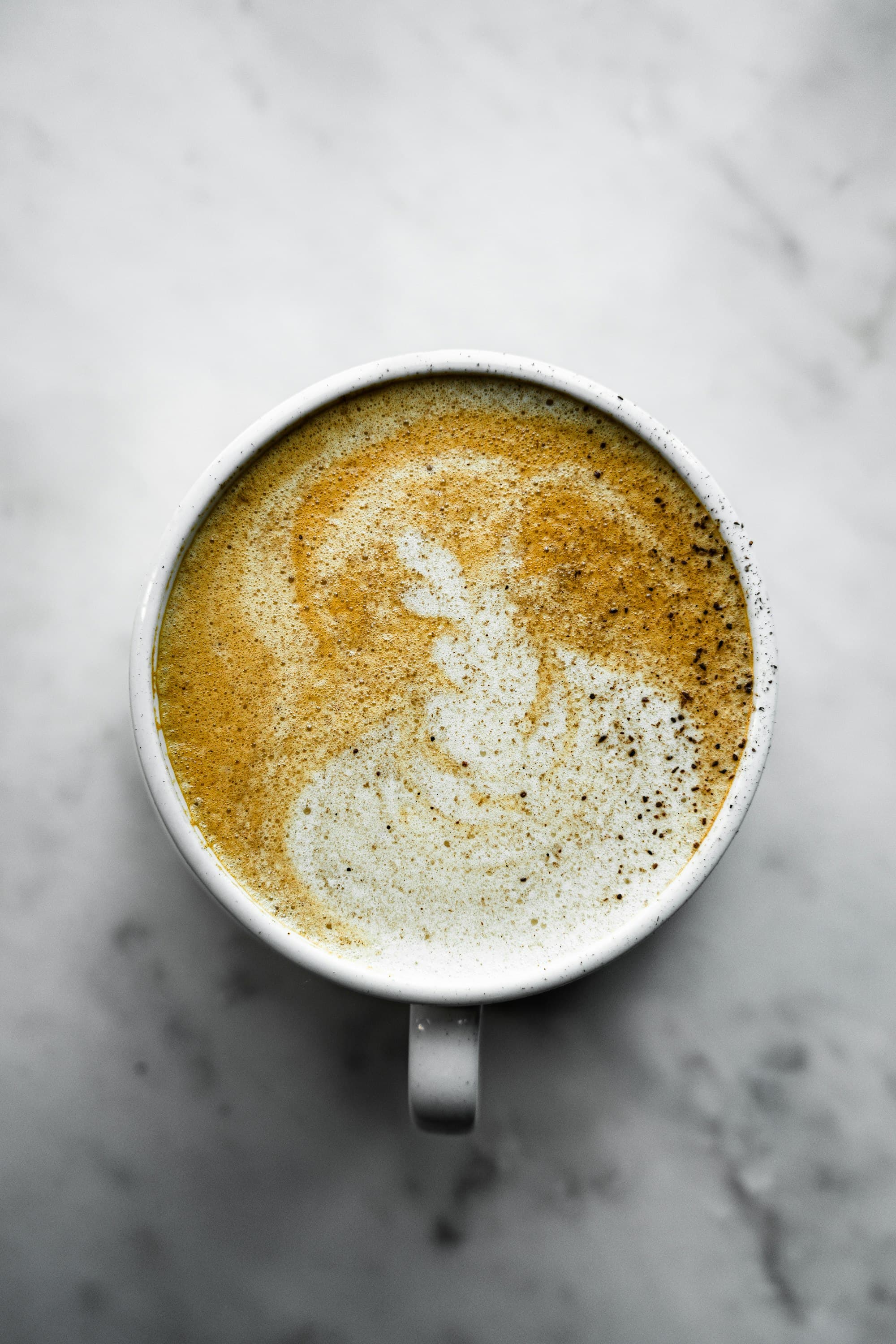 Cappuccino con schiuma decorata, visto dall'alto su un tavolo in marmo chiaro