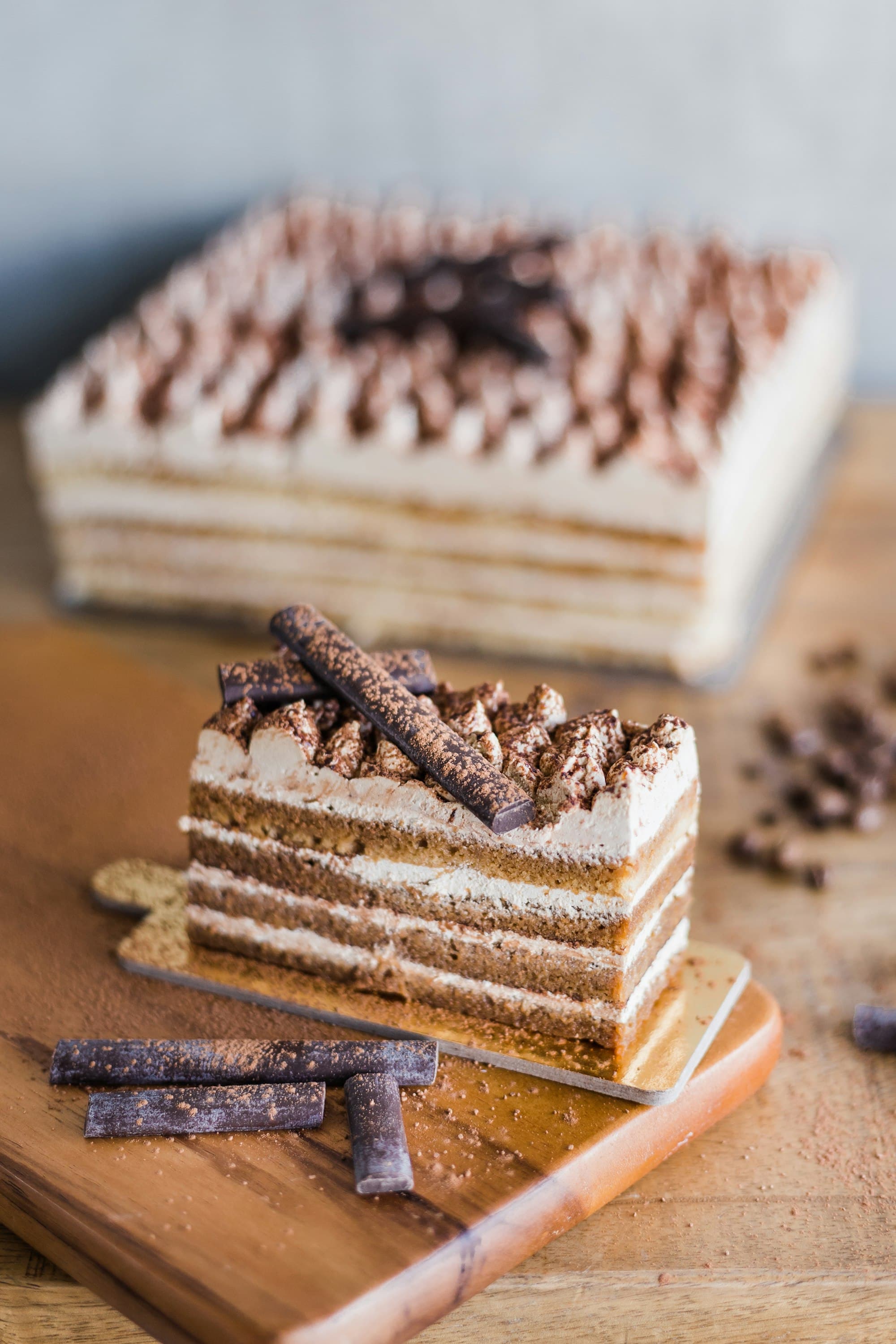 Fetta di torta a strati con crema al mascarpone e cacao, decorata con cioccolato fondente