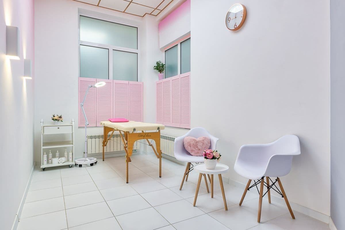 Angolo relax dello studio con poltrone bianche, tavolino e composizione di fiori rosa