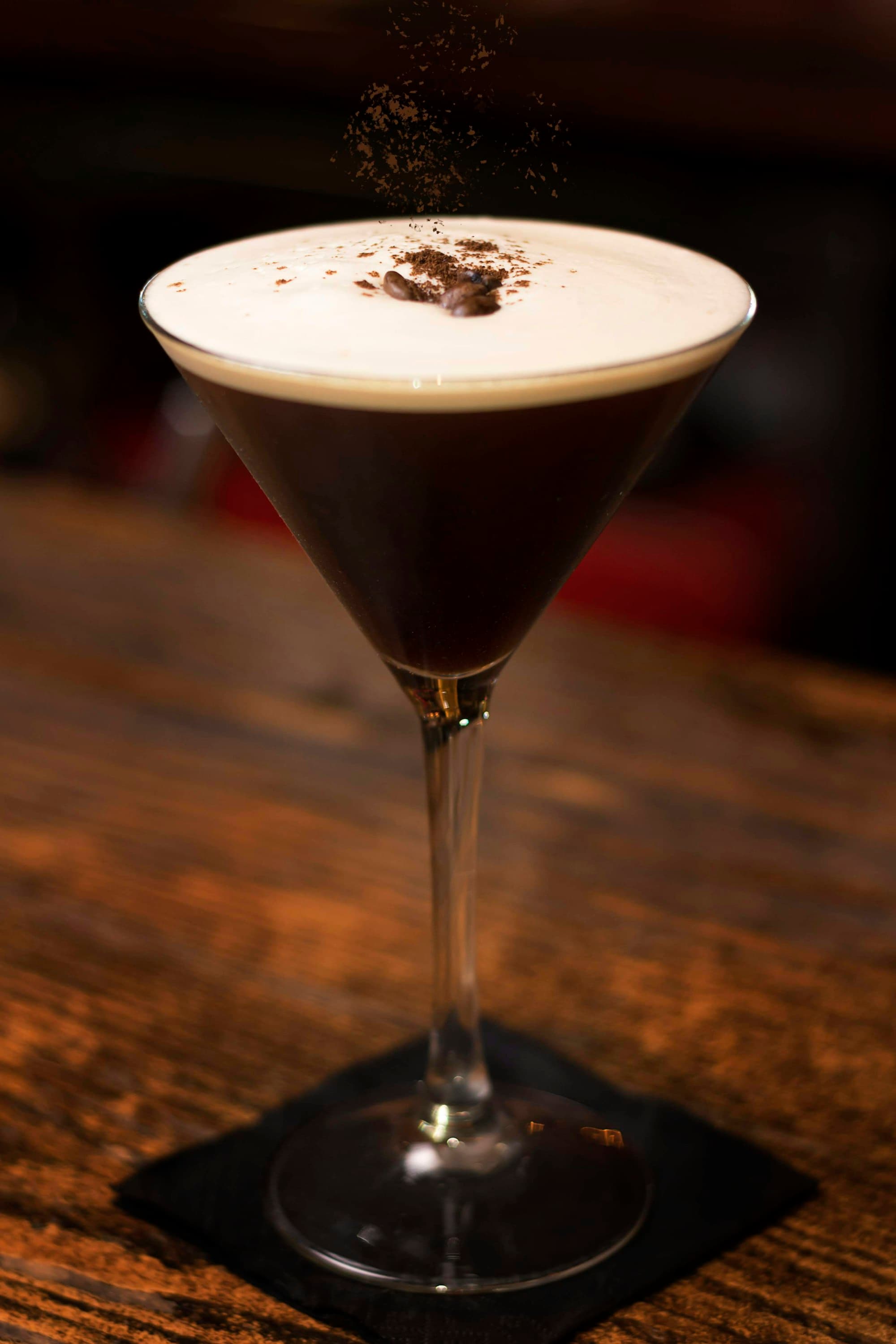Espresso martini con schiuma cremosa e chicchi di caffè su un tavolo di legno scuro