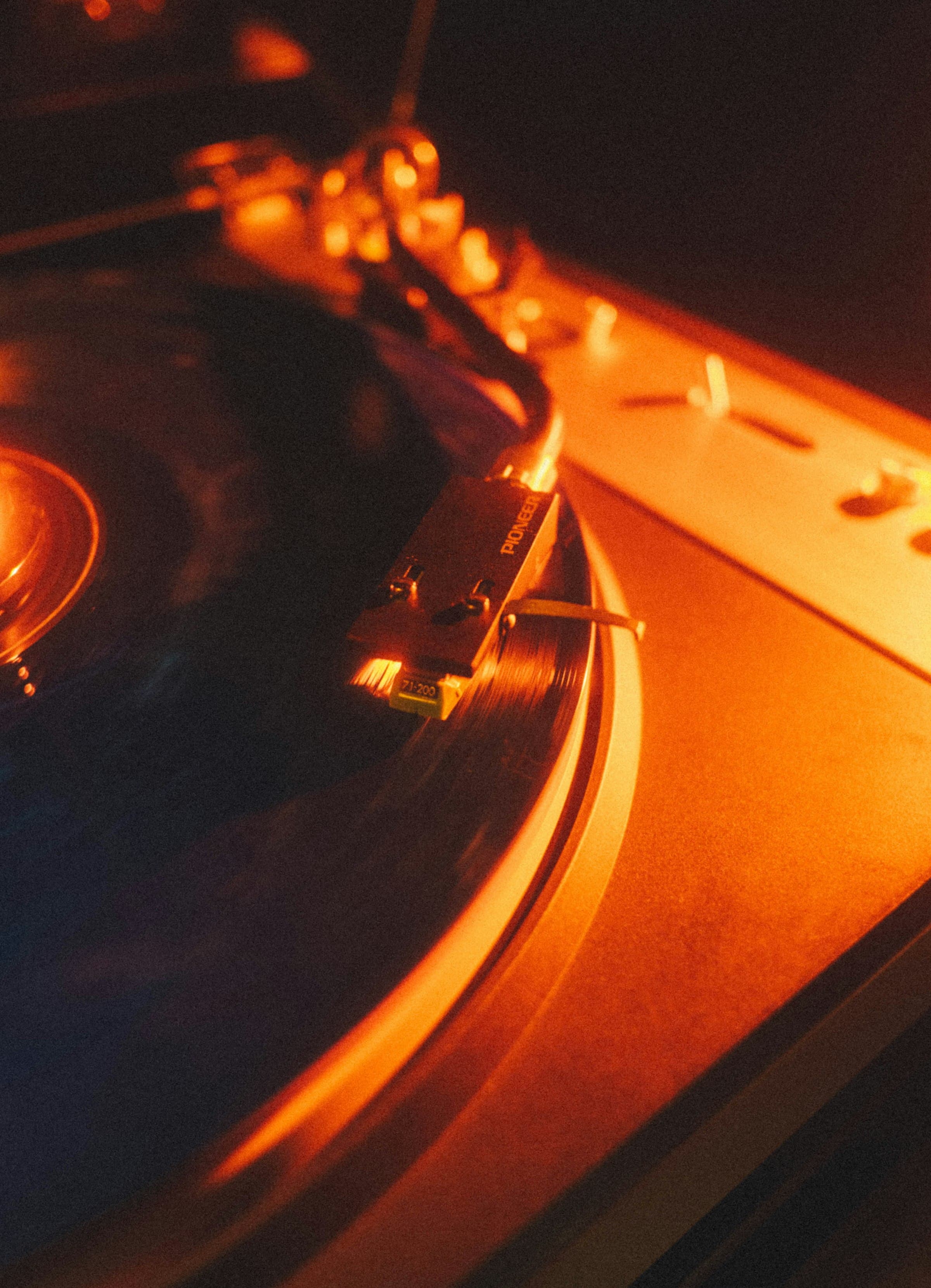 Primo piano di un giradischi Pioneer illuminato da una luce calda ambrata durante un DJ set