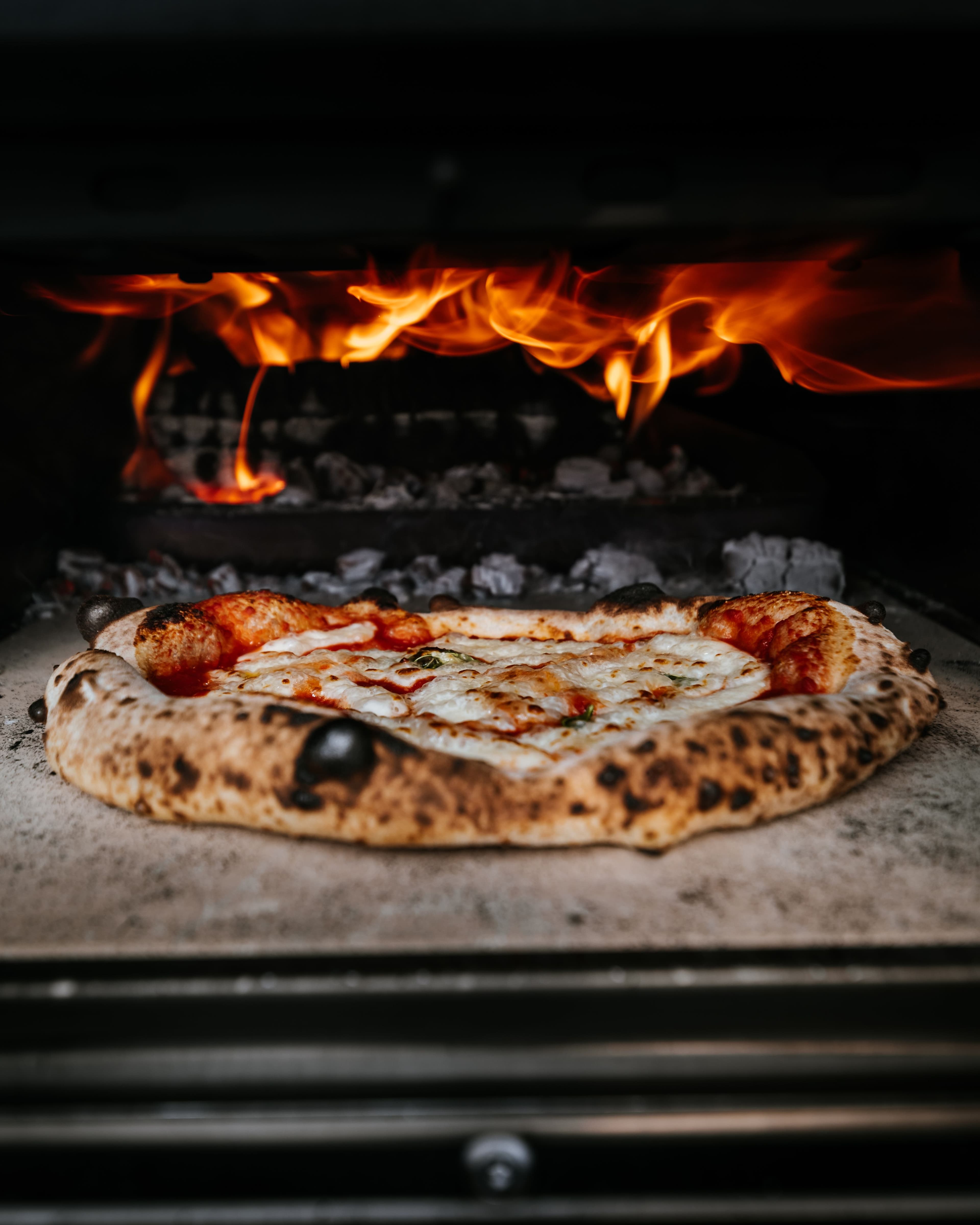 Pizza margherita che cuoce nel forno a legna acceso