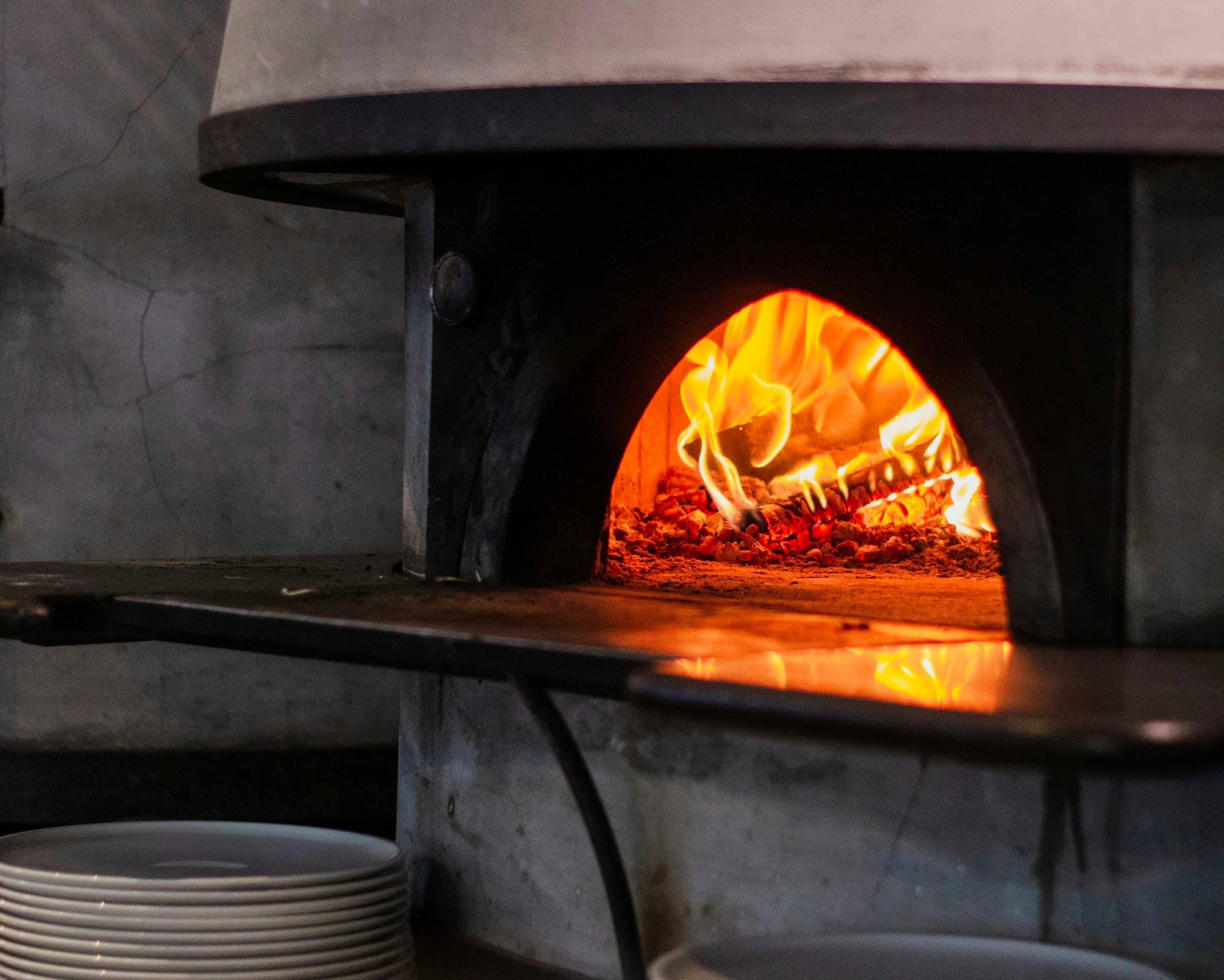 Bocca del forno a legna acceso di Fiamma, con le fiamme vive pronte a cuocere la prossima pizza
