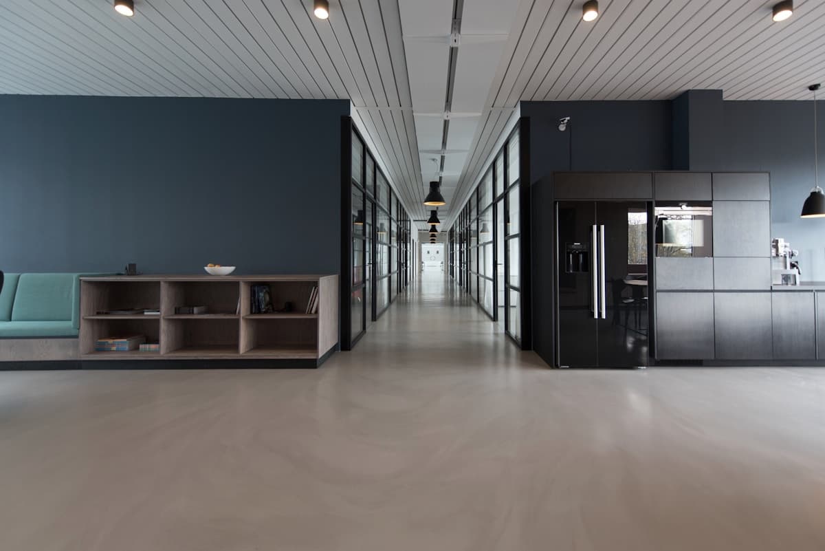 Corridoio interno con pareti scure e cucina illuminata sullo sfondo